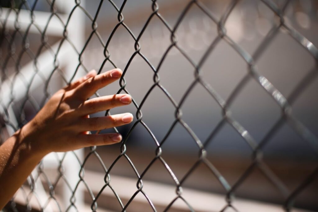 Person touching a fence while on a UK prison visit after notarisation